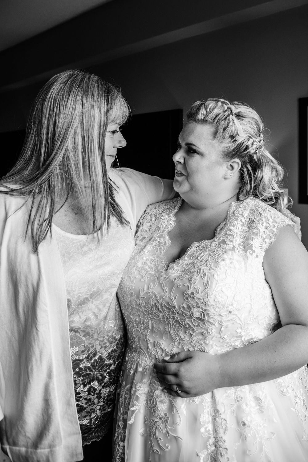 Black and white photo of mother and daughter sharing an intimate moment in wedding attire.