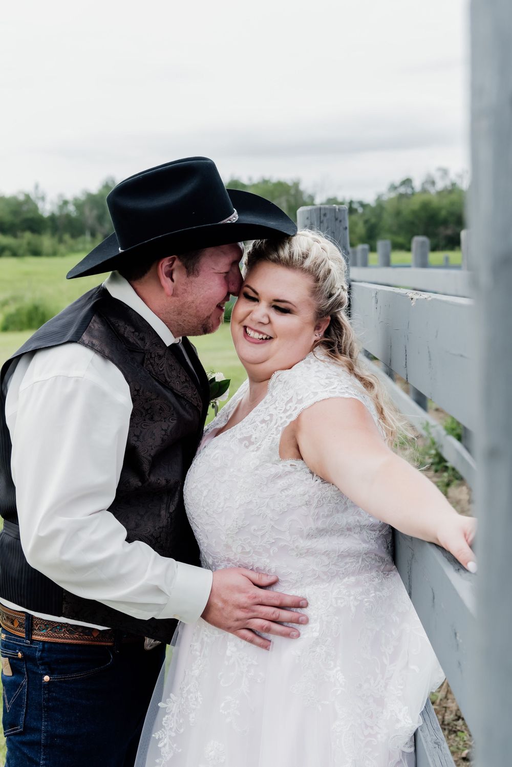 A romantic western-style wedding photo with the couple sharing an intimate moment against a rustic backdrop.