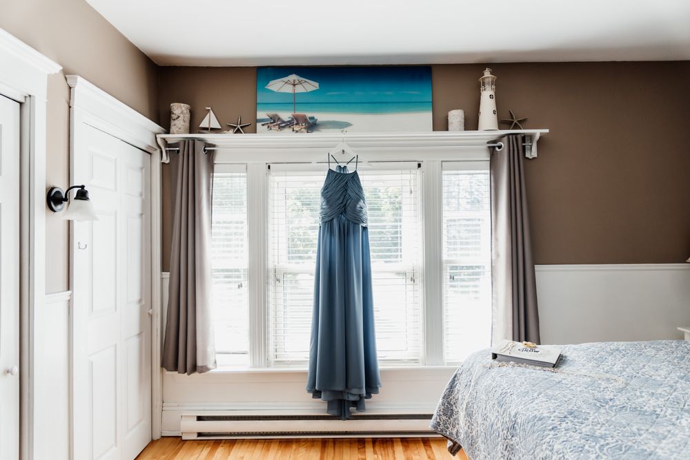 Blue formal dress hangs in bedroom with white trim and brown walls.