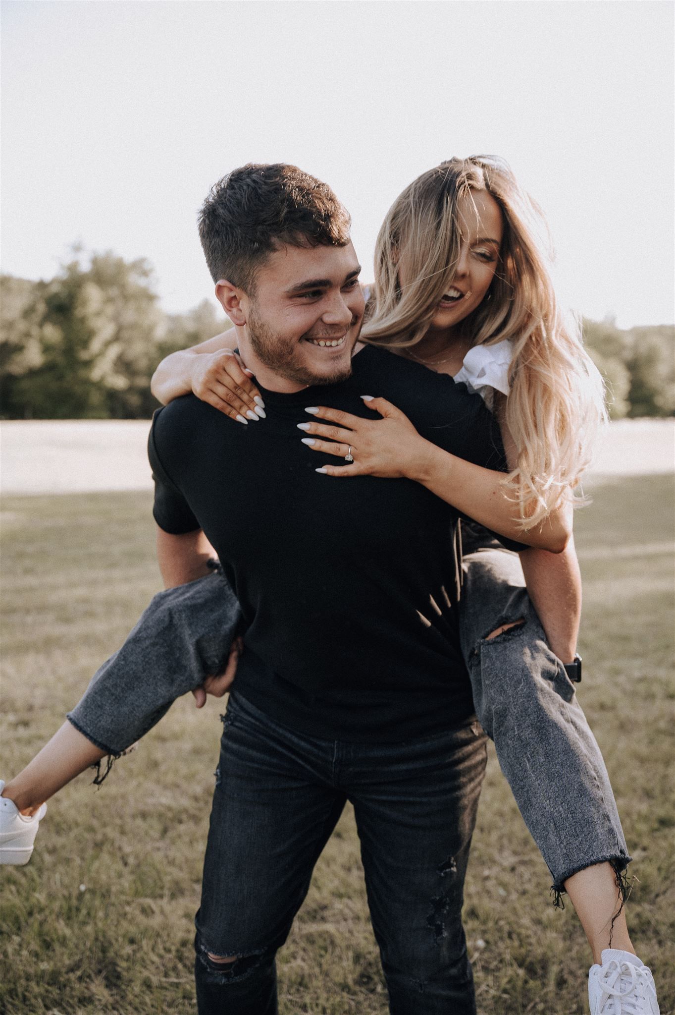 Couple sharing a piggyback ride moment in a sunny field.