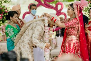 Traditional Indian wedding ceremony with ritual exchanges under pink floral decorations.