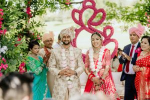 Garden wedding celebration with traditional Indian attire under floral archway.