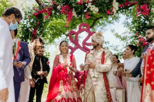 Outdoor wedding celebration with red and white floral decorations and heart-shaped backdrop.