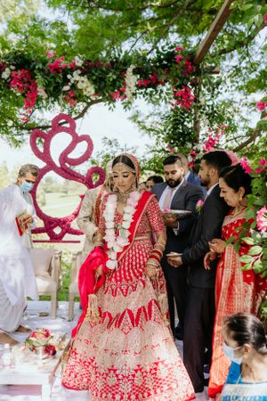 Wedding ceremony with red and white floral decorations and heart-shaped backdrop design.