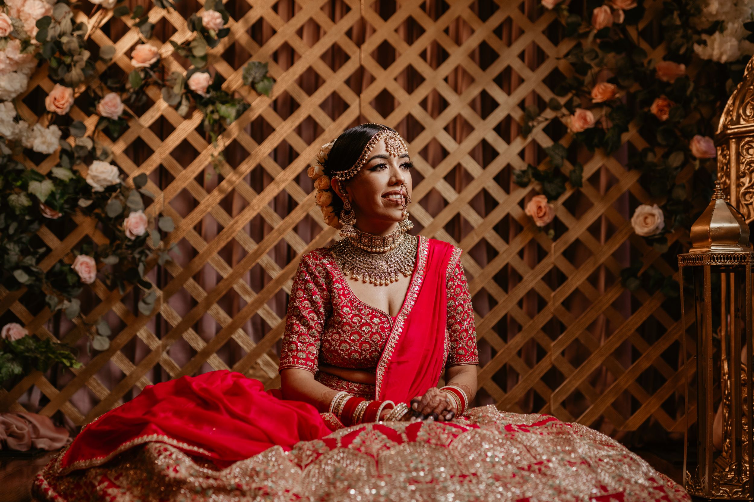 South Asian bridal portrait showcasing intricate jewelry and red embroidered wedding attire.