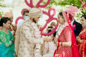 Traditional wedding ceremony exchange under pink heart decorations in garden setting.