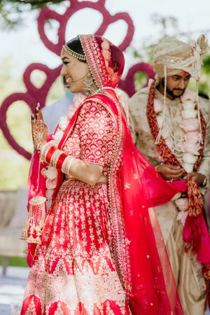 Wedding ceremony under floral arch with decorative red heart design and traditional attire.