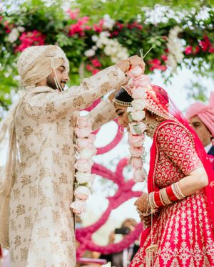 Traditional garland exchange ceremony during Indian wedding with bright floral decorations.