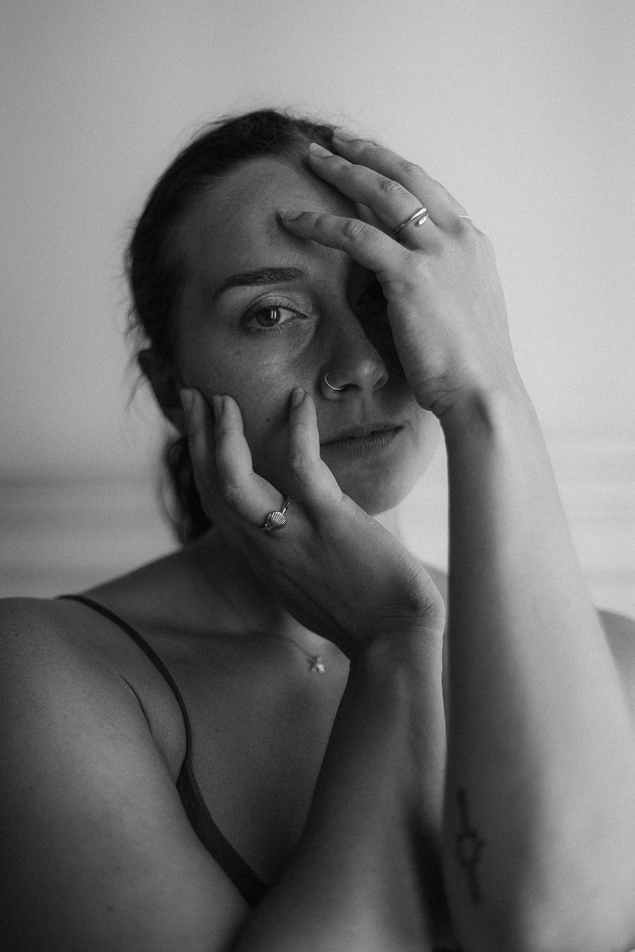 An artistic black and white portrait shows someone framing their face with their hands.