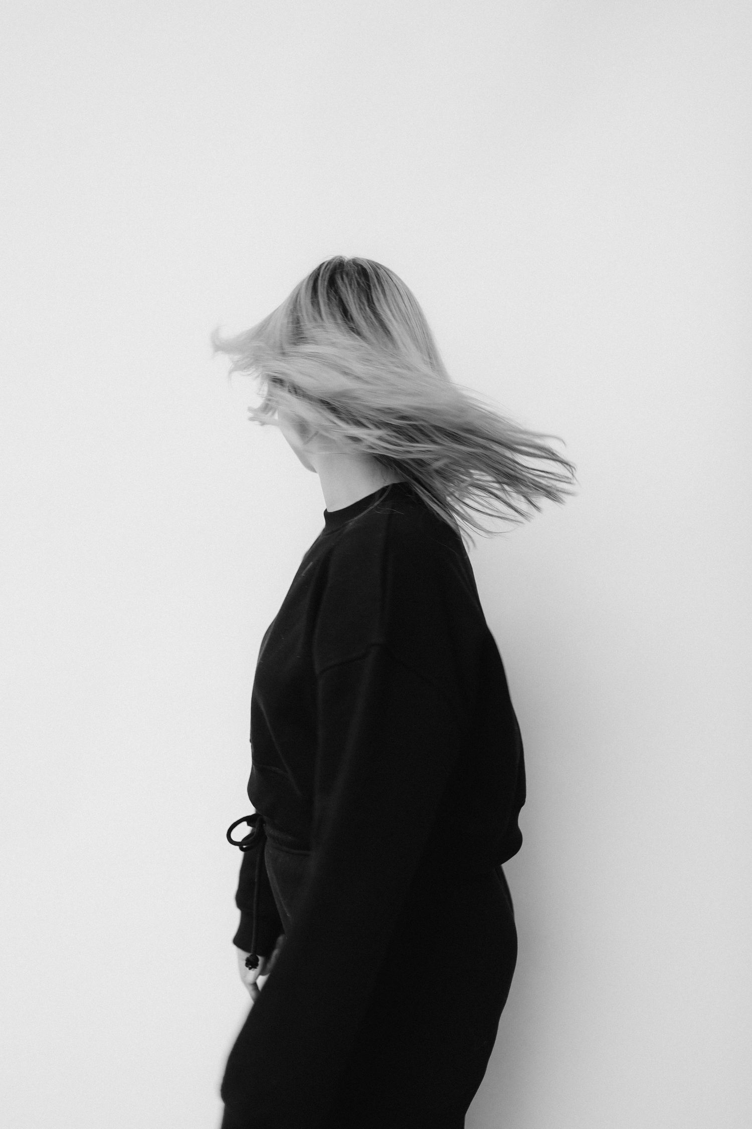 Minimalist black and white photo showing hair movement against white background.