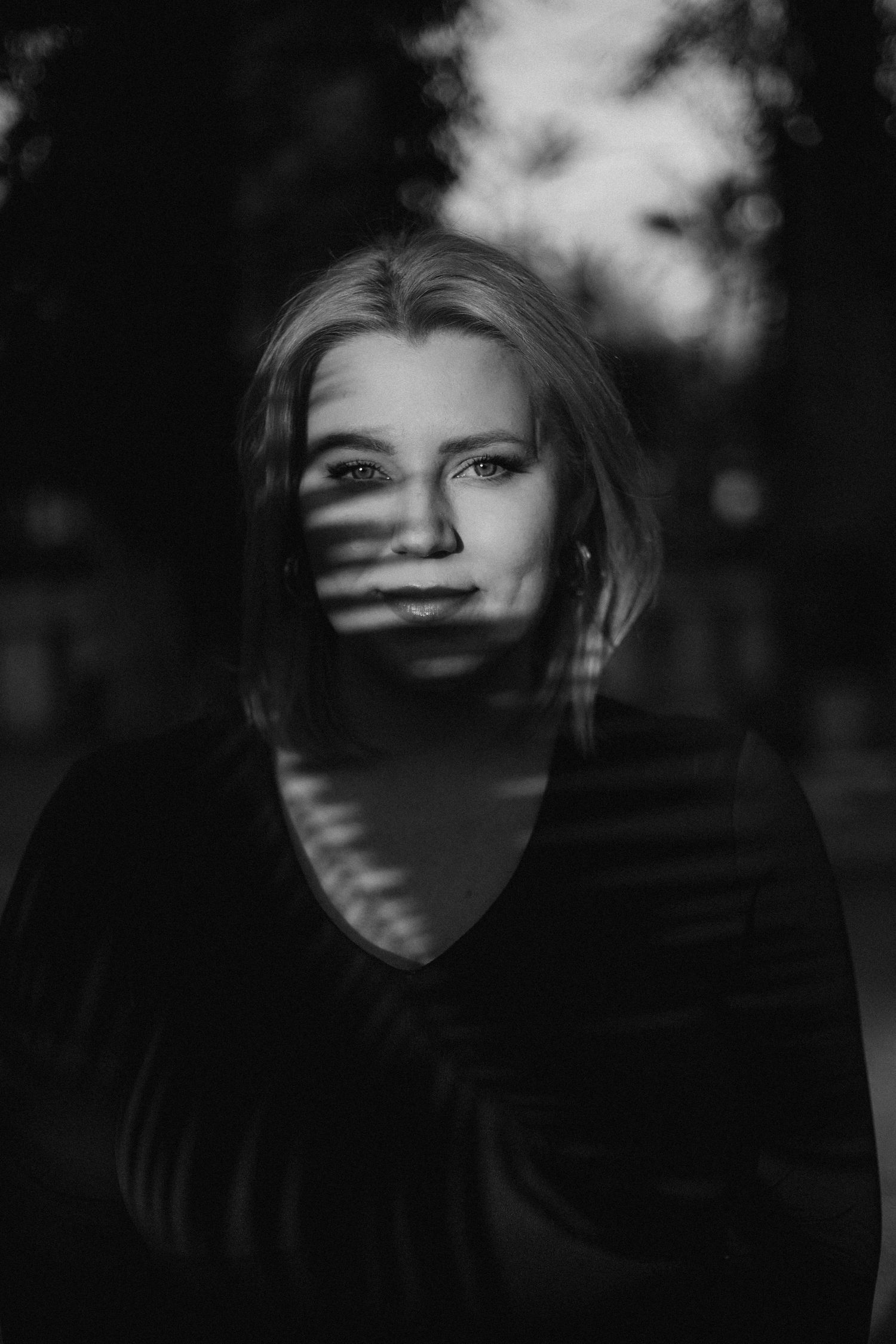 Dramatic black and white portrait with shadow patterns creating an artistic effect.