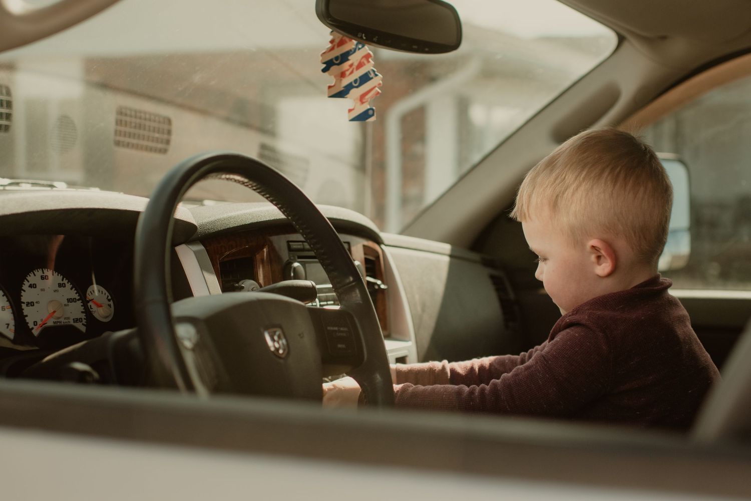 Little boy pretending to drive his dads truck