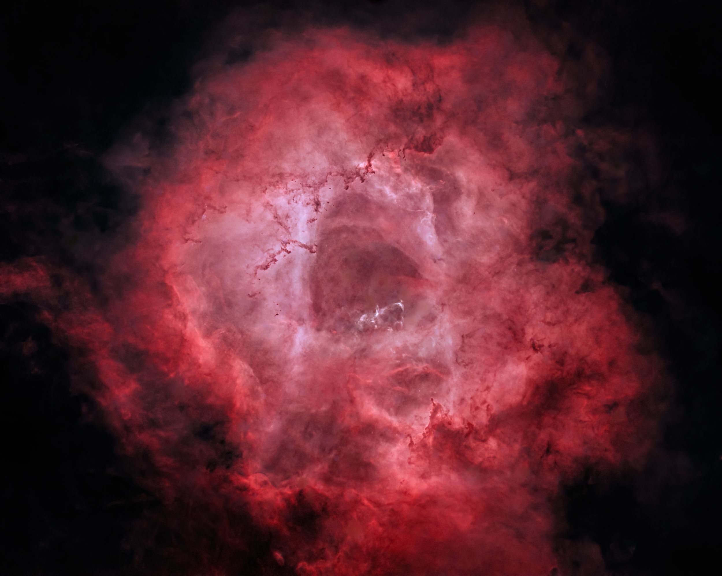 A detailed view of the Rosette Nebula's central region showing intricate red gas formations in deep space.