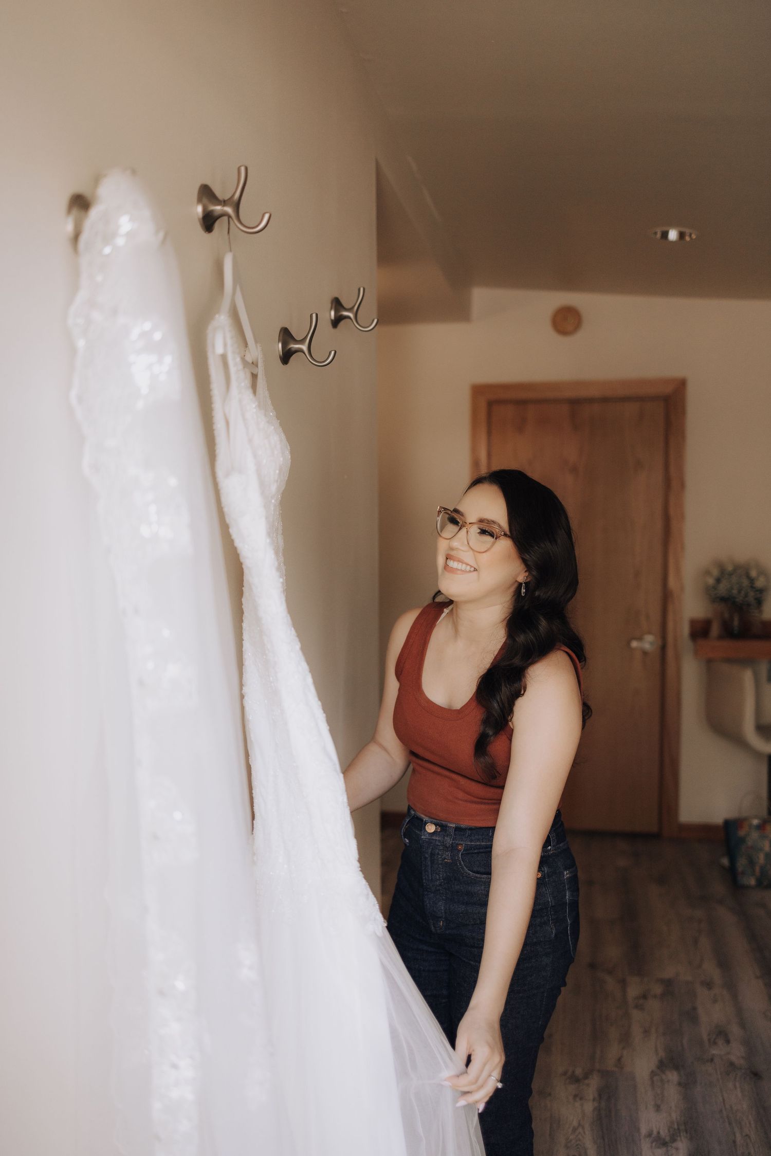 Someone admiring a white wedding dress hanging on a wall.