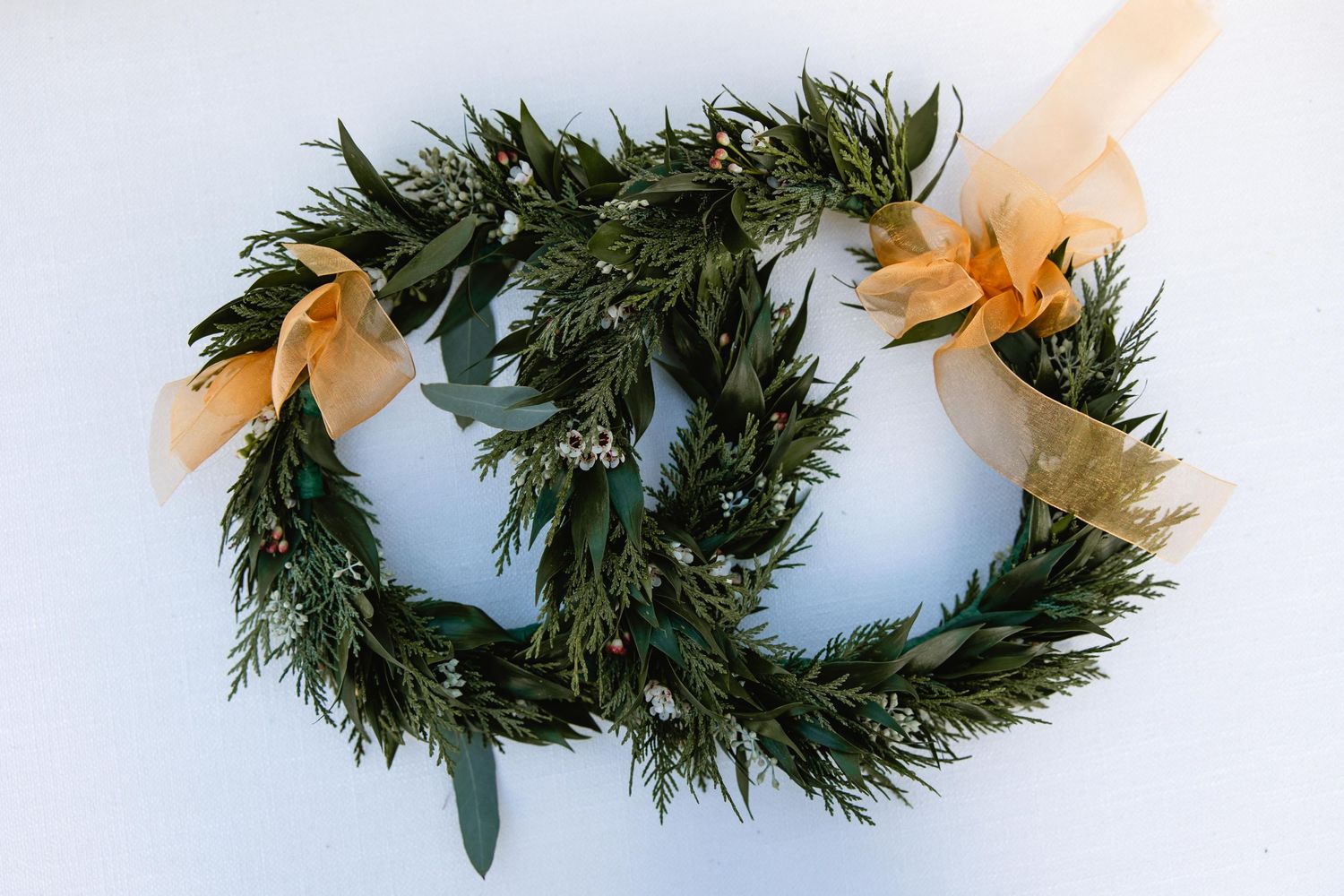 Evergreen wreaths and garlands arranged against a light blue background.