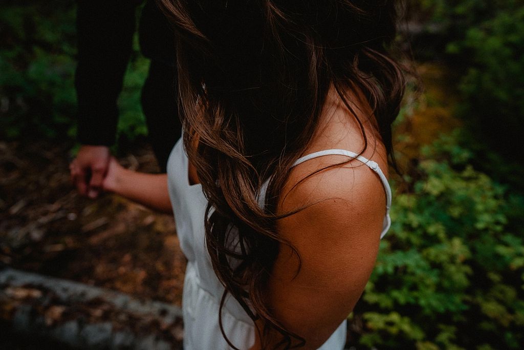 Romantic couple shares an intimate moment in a lush forest setting at sunset.