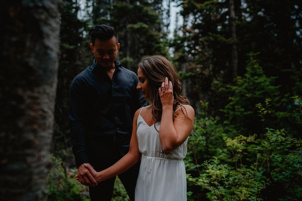 Dancing together on a wooded trail surrounded by evergreen trees.
