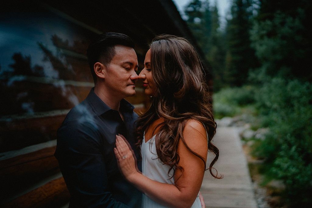 Couple sharing a tender moment on a forest path at dusk.