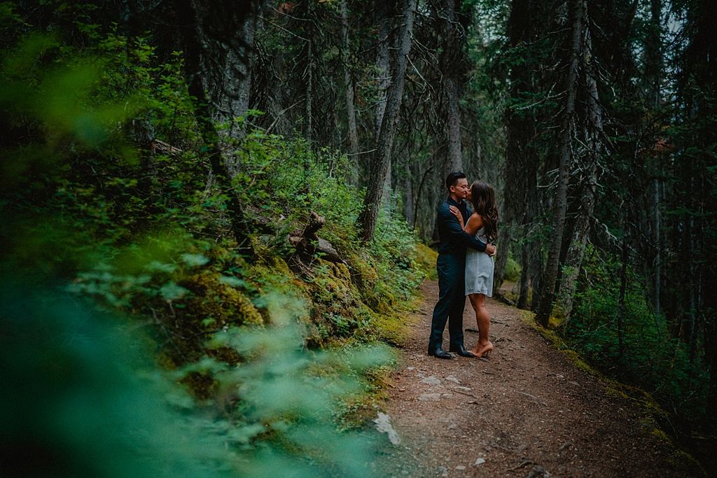 Intimate forest engagement session captured through natural foliage.