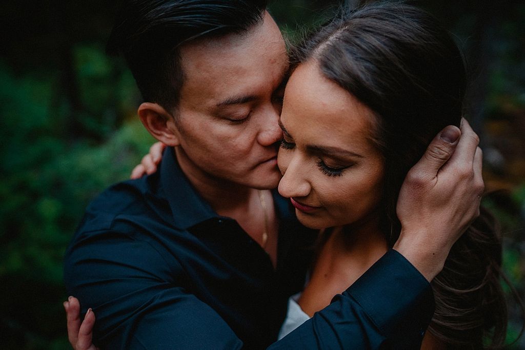Romantic couple sharing an intimate moment in a forest setting.