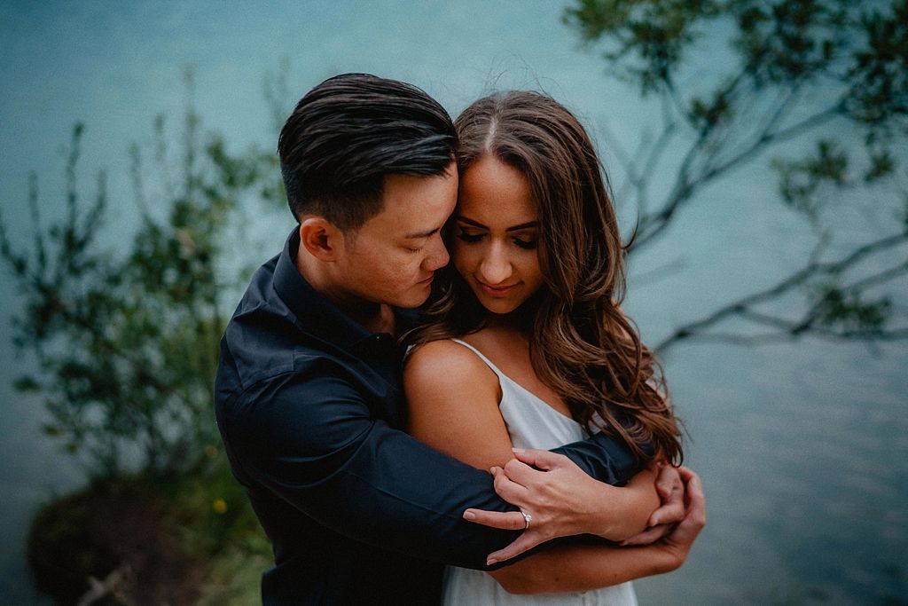 Intimate couple portrait against a serene lake backdrop.