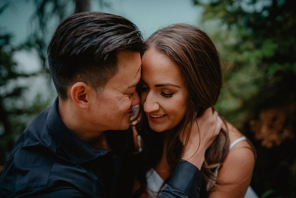 Intimate close-up portrait of a couple against blurred greenery.