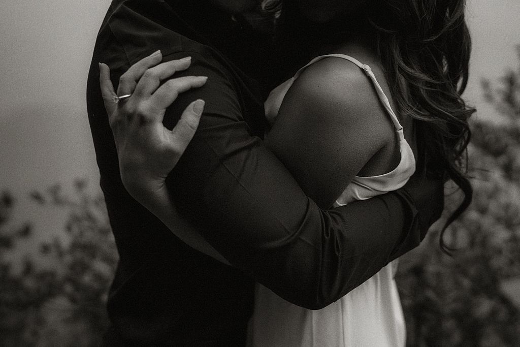 Black and white portrait of an embrace showing hands and flowing fabric.