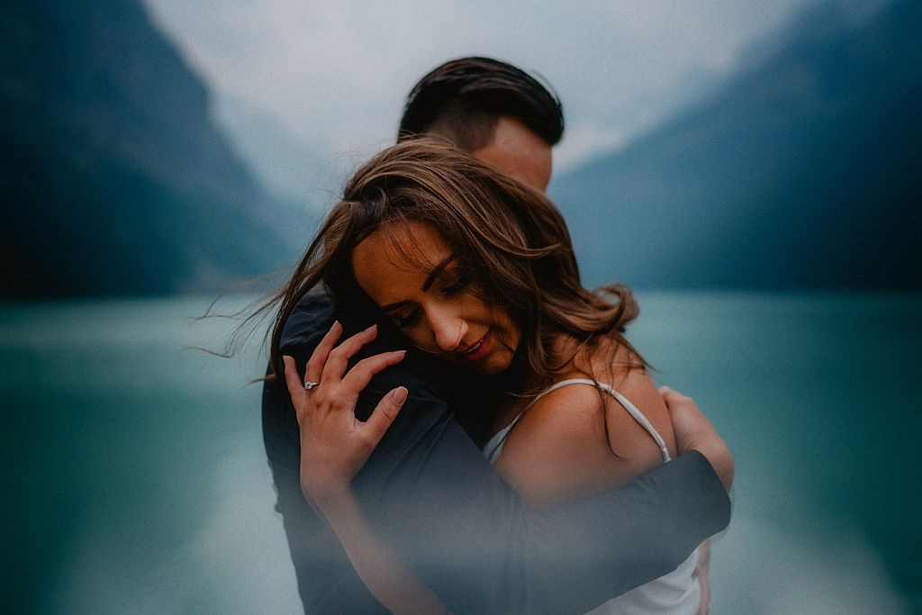 Intimate portrait by turquoise mountain lake with soft moody lighting.