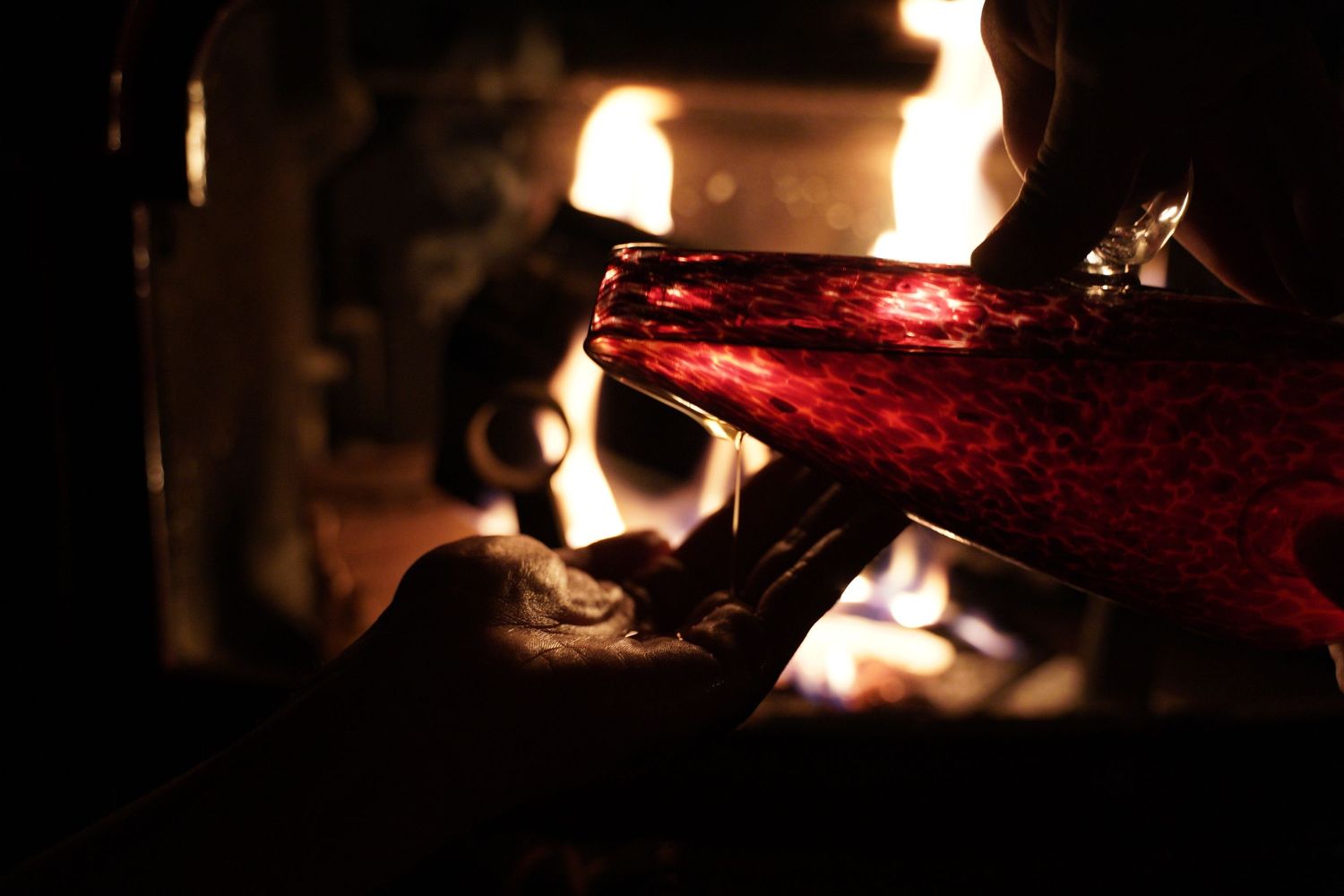 Red wine being poured in dramatic lighting against dark background.