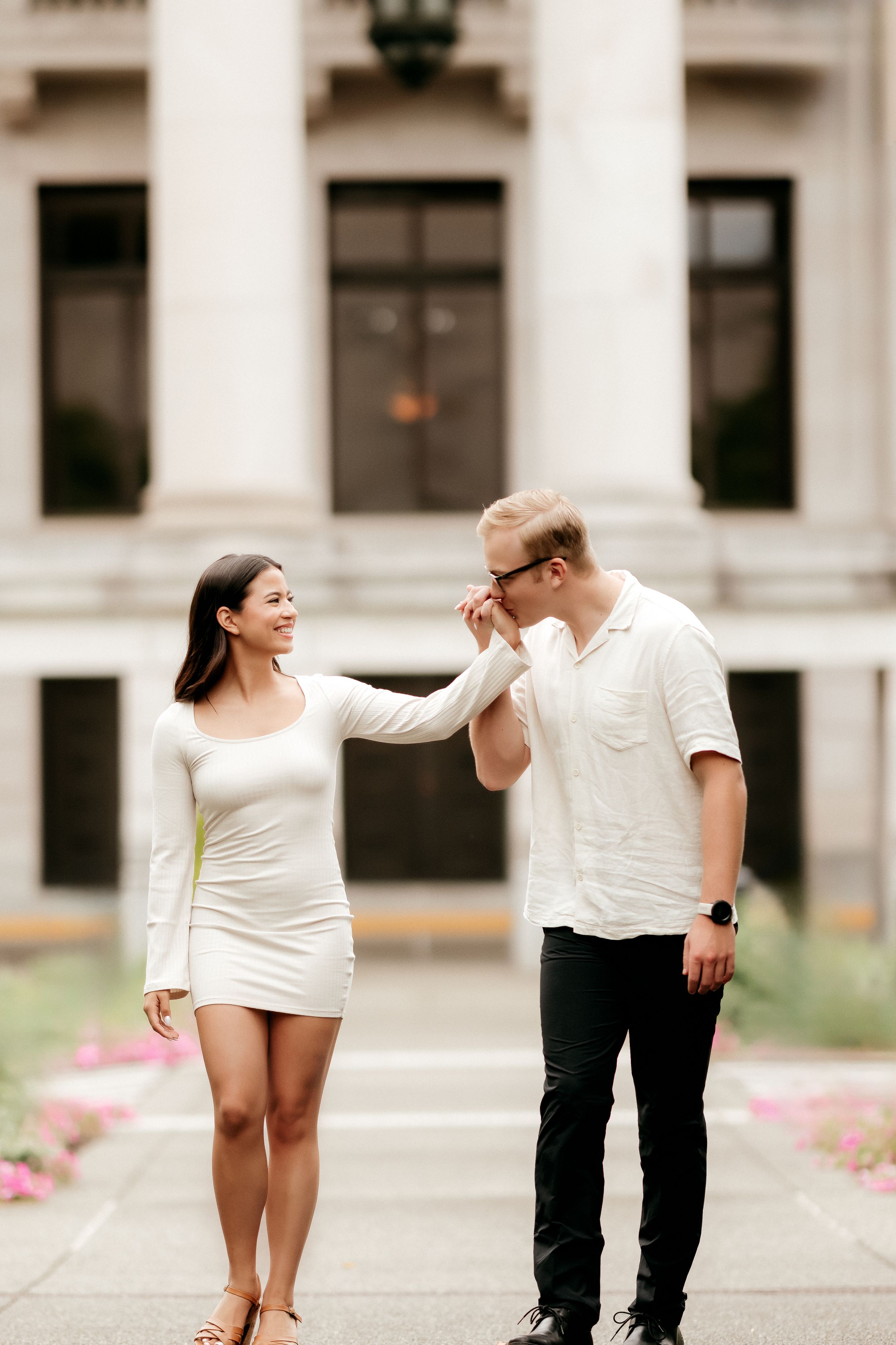 A romantic moment between a couple in formal attire by a classical building entrance.