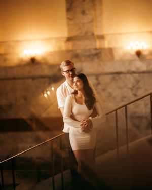 Intimate couple portrait on elegant marble staircase with warm lighting.