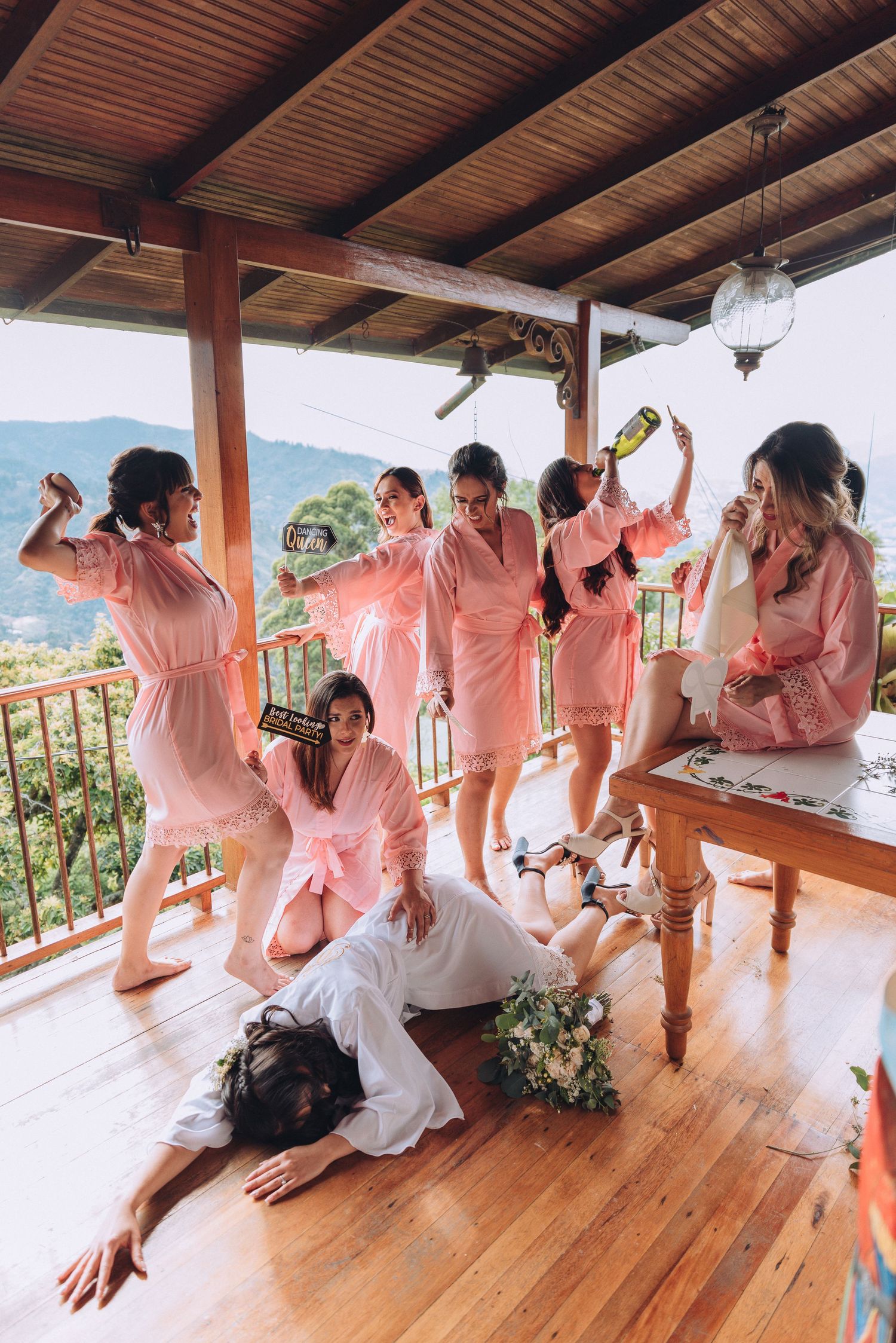 Group celebrating in pink robes on a covered porch with mountain views.