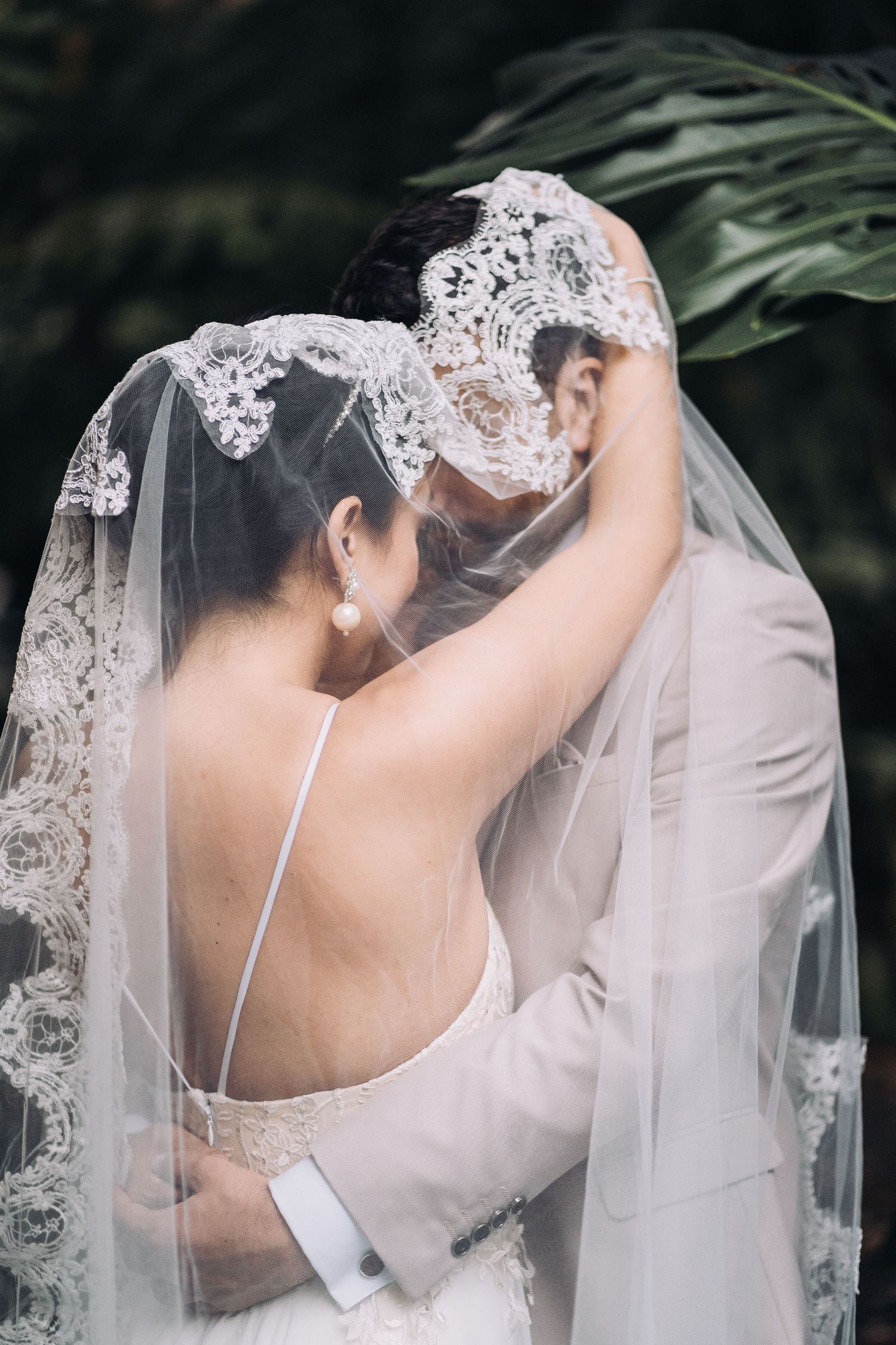 A romantic moment under an elegant lace veil during an outdoor wedding ceremony.