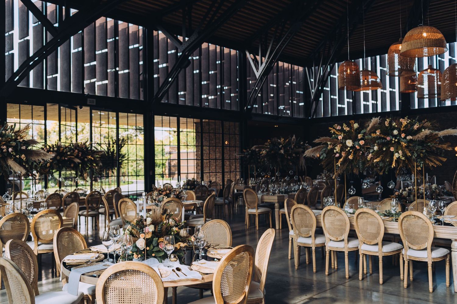 Elegant wedding reception venue with French-style chairs and dramatic industrial ceiling details.