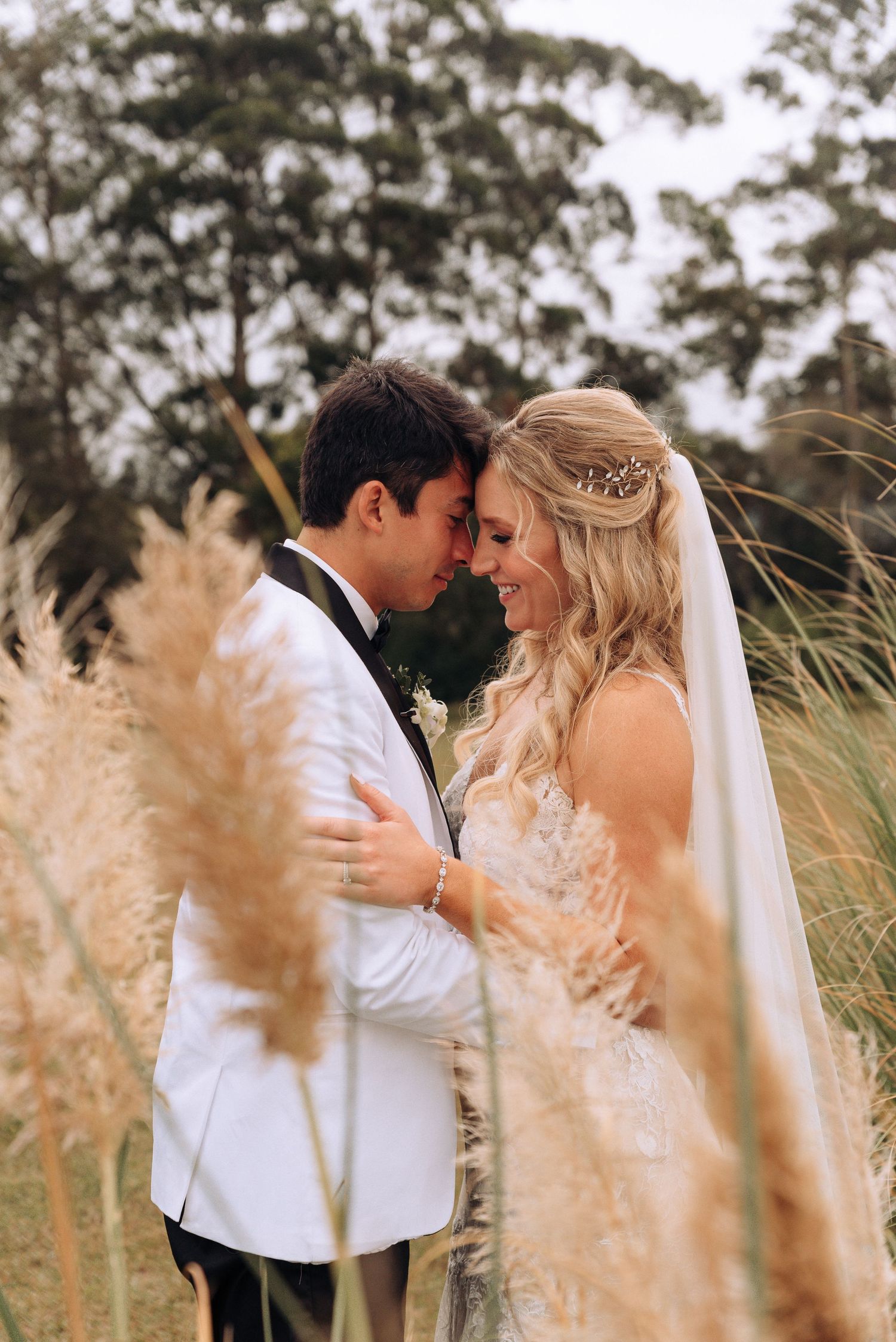 Intimate moment captured among tall pampas grass during wedding photoshoot.