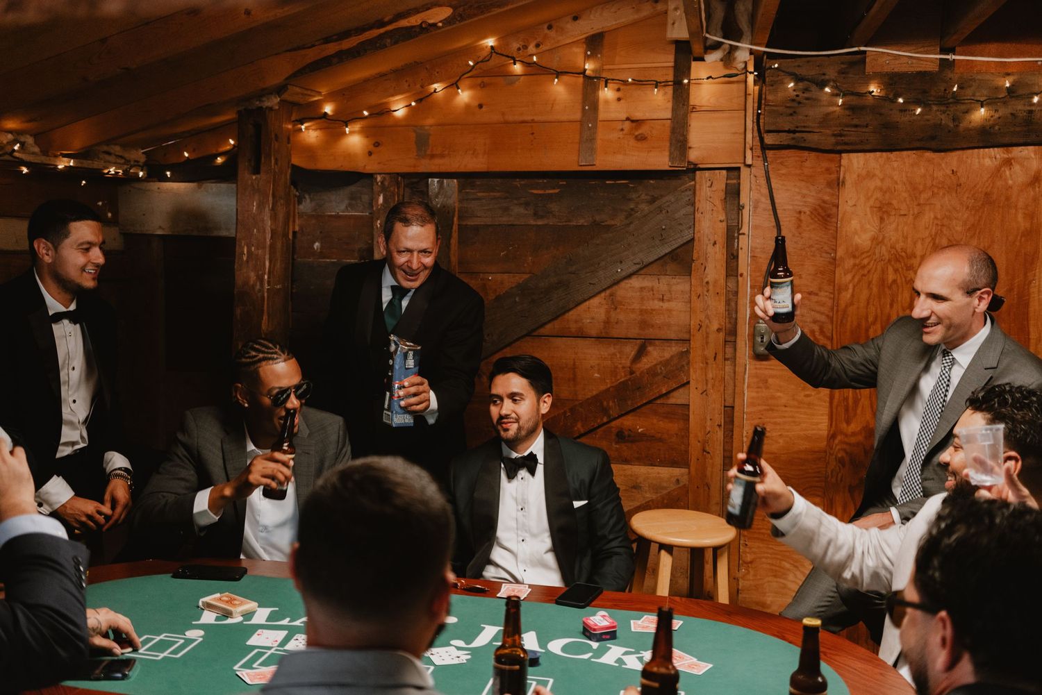 Groomsmen enjoying a game of poker at a rustic wooden table.