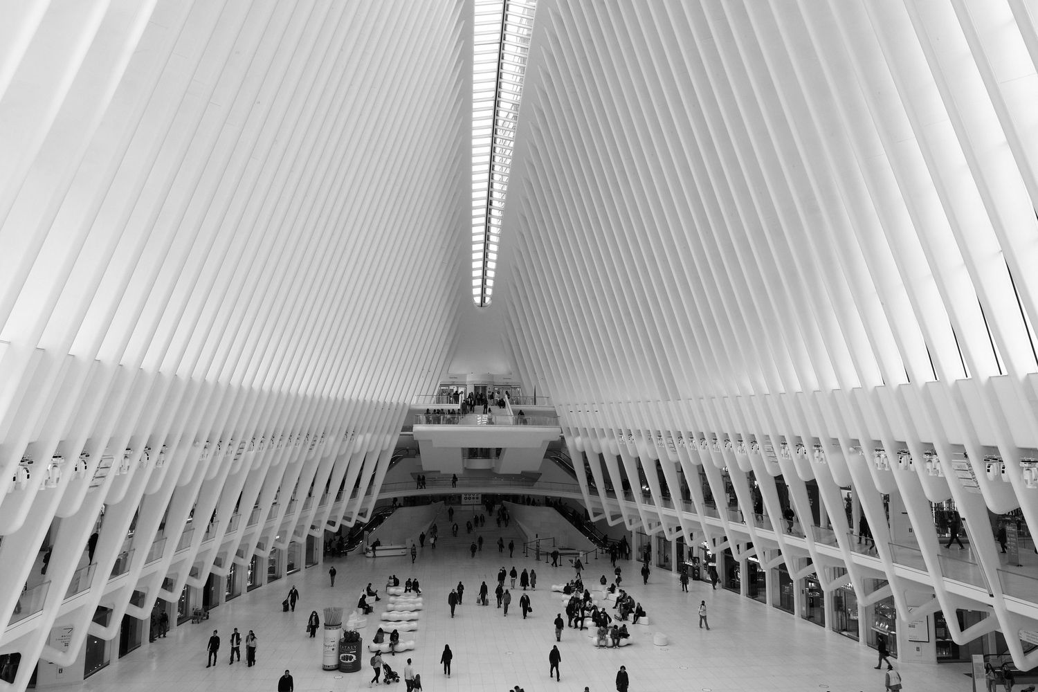 Interior of the Oculus transportation hub showing white ribbed architecture and people below.