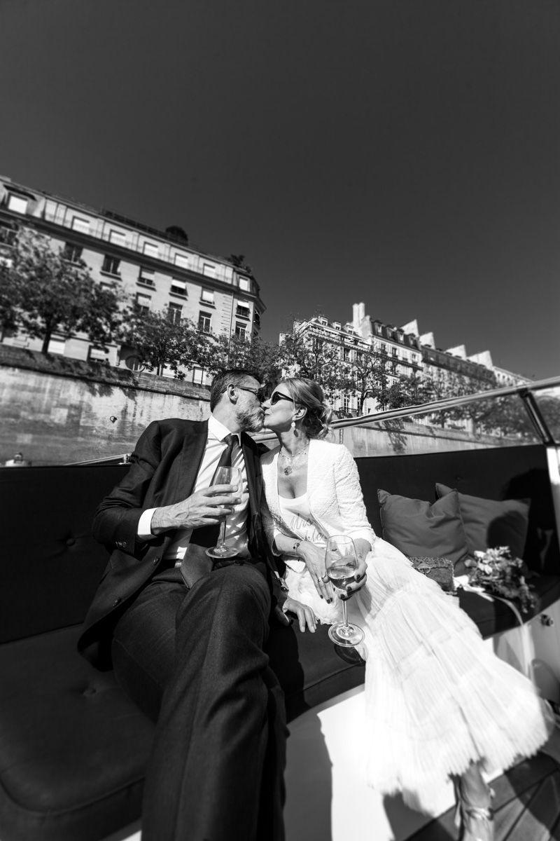 Black and white photograph of a romantic boat ride with cityscape background.