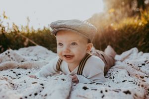 A child rests on a white blanket outdoors during a photo session.