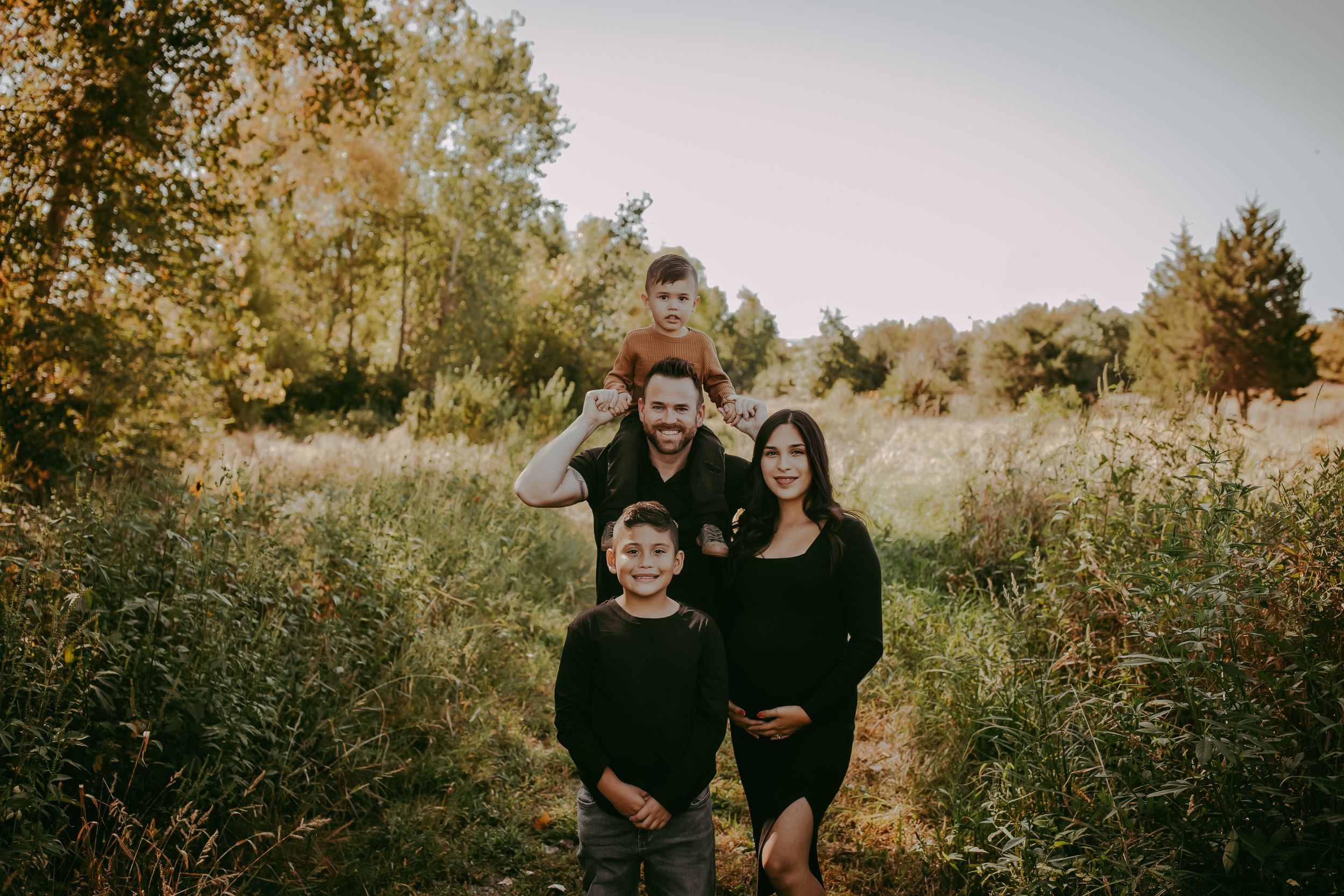 Family portrait of group in black outfits standing in autumn field.