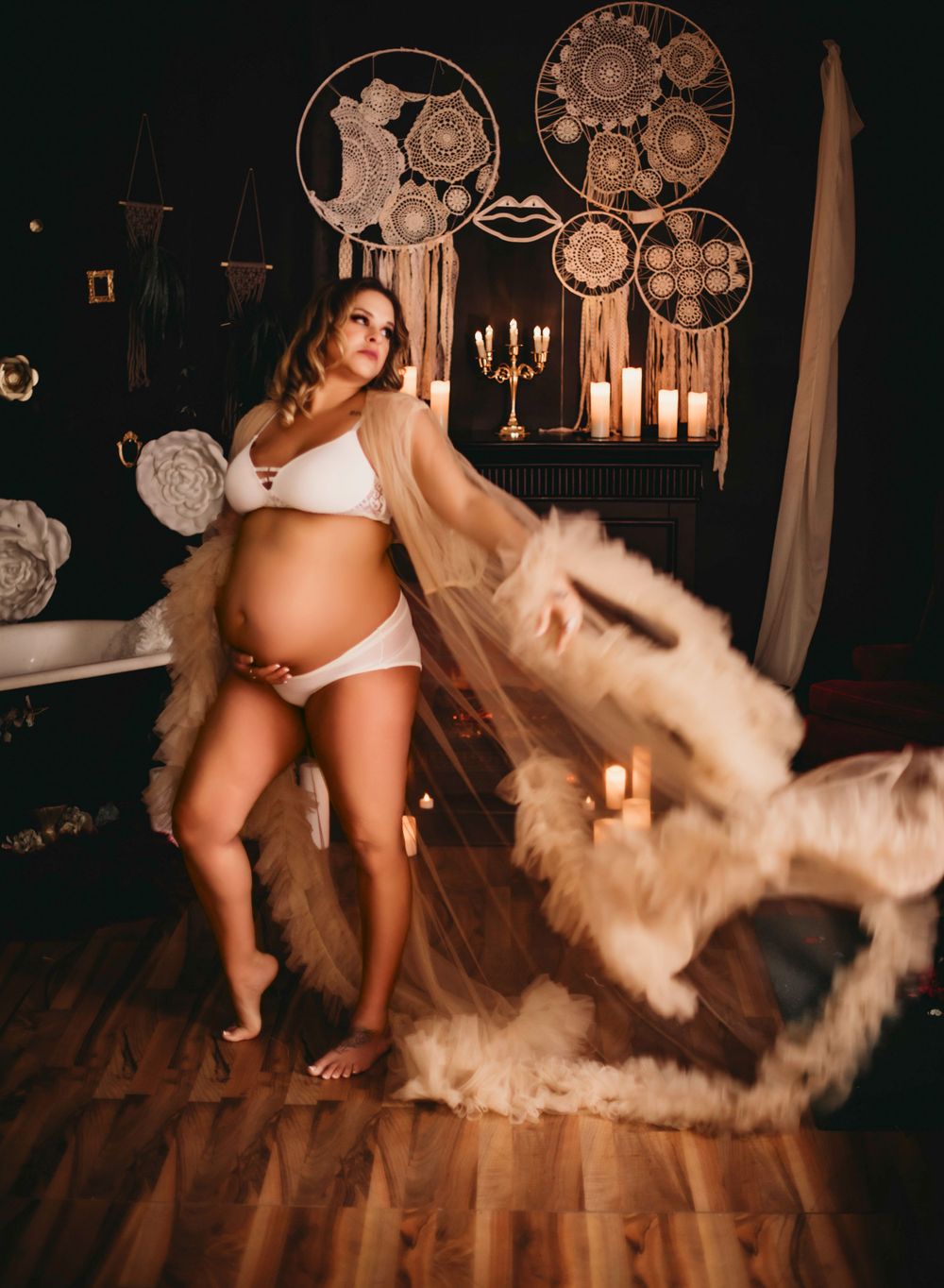 A maternity photo with dreamcatchers and candlelight in a bohemian setting.