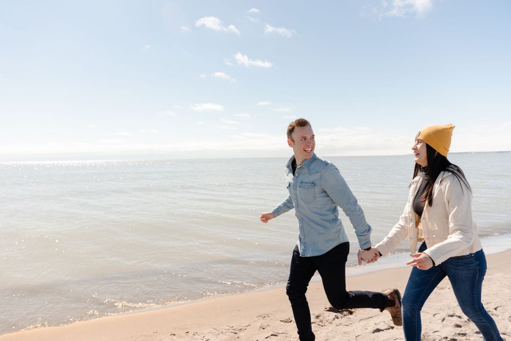 A couple holding hands while running on the beach.
