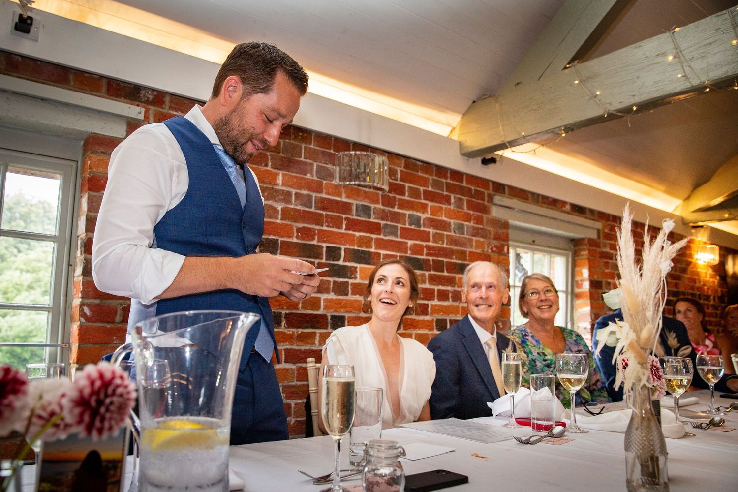 Indoor wedding reception at a rustic brick-walled venue with elegant table settings.