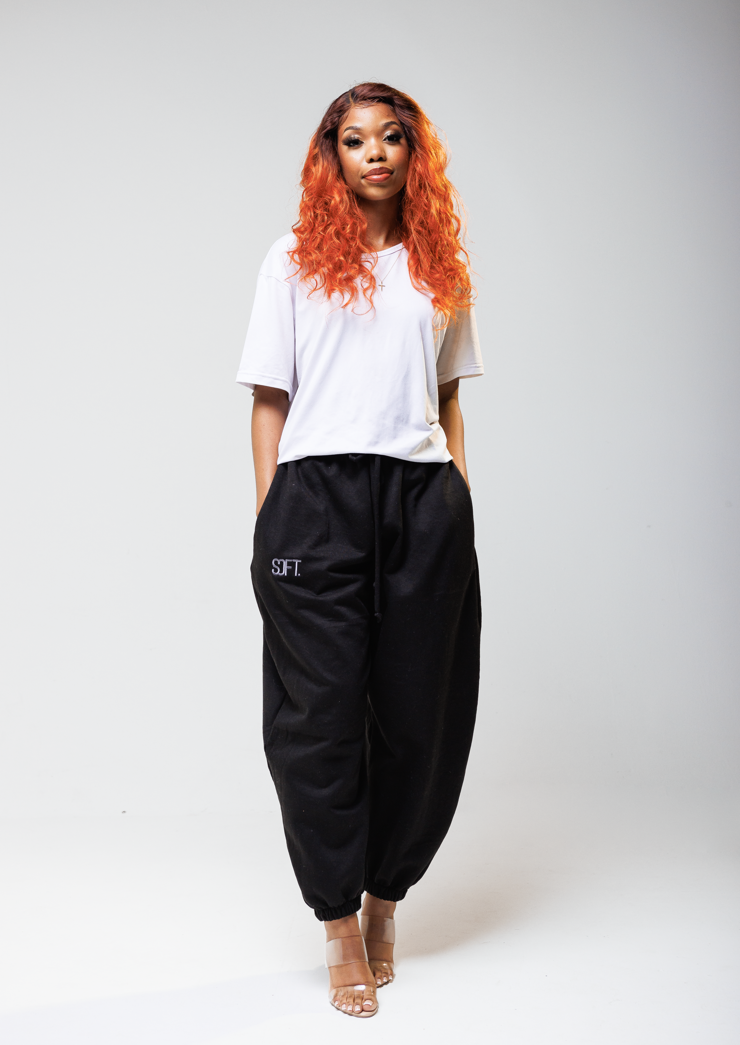 Model wearing white t-shirt and black jogger pants poses against white background.