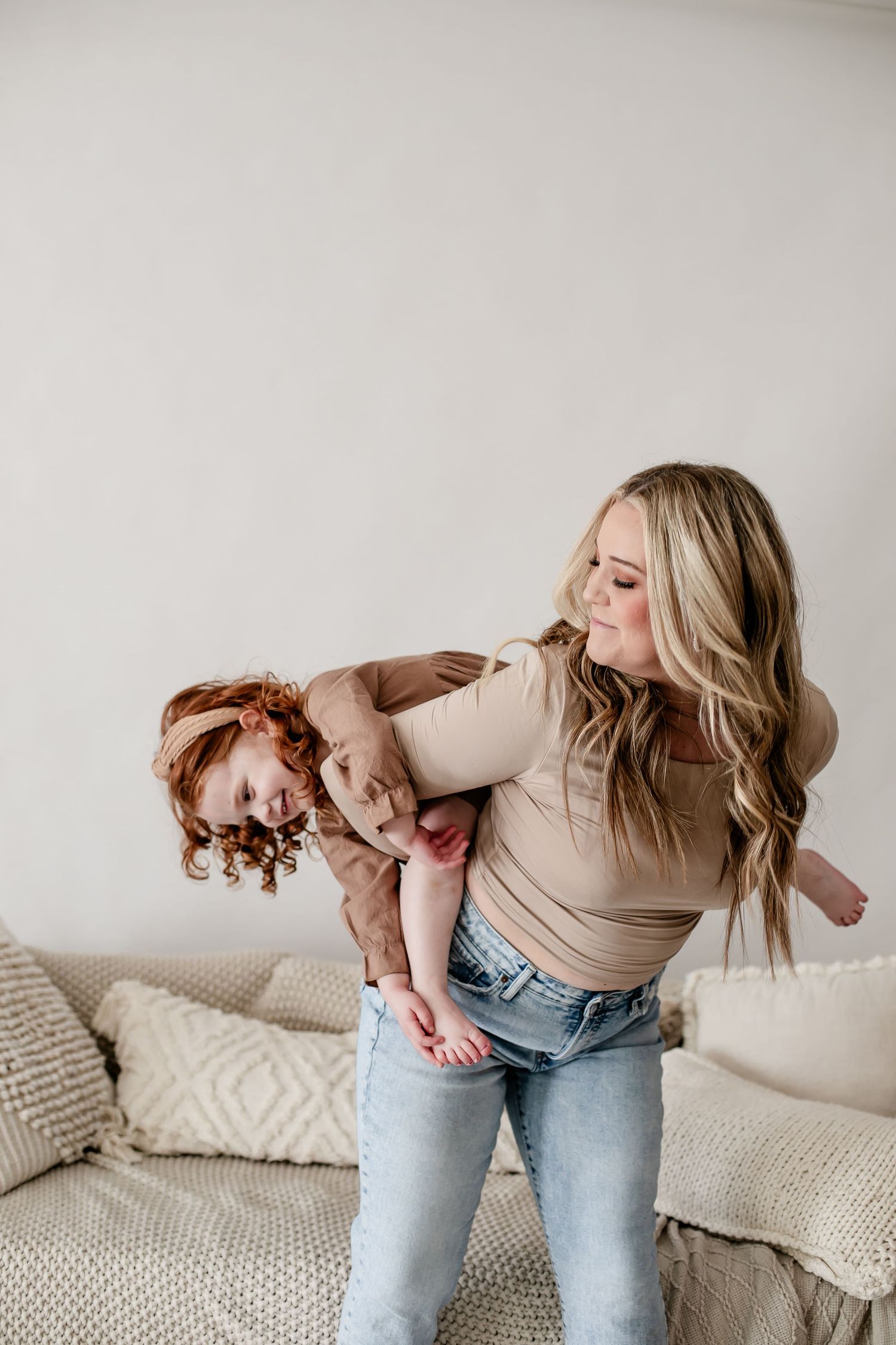 Candid moments of affection and laughter against a white wall with decorative pillows.