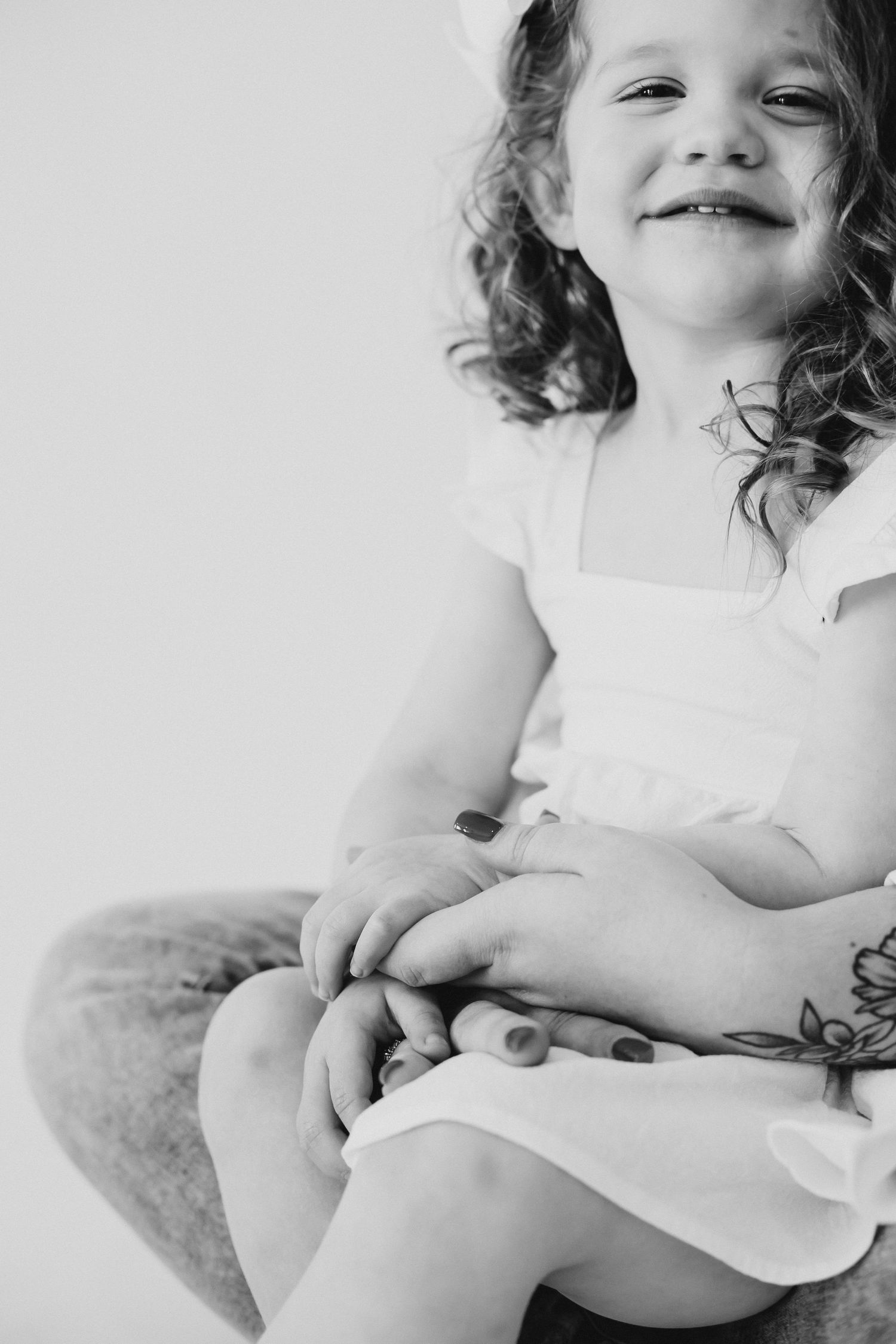 Black and white portrait of child in white dress smiling.