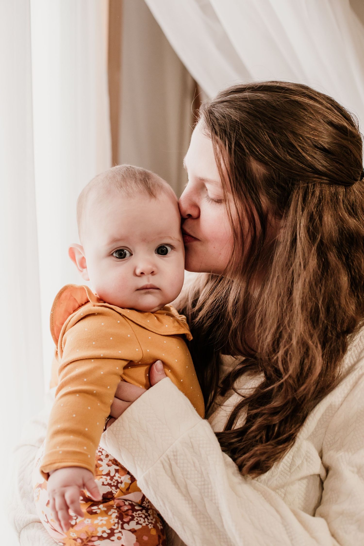Tender moments of affection with a baby wearing an orange outfit.
