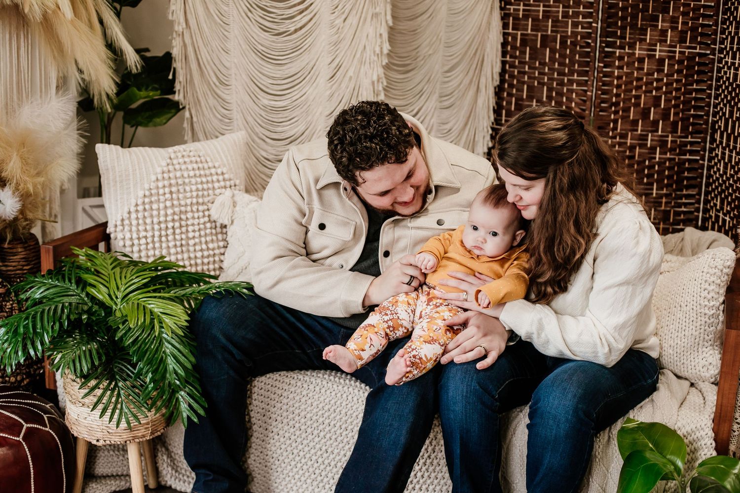 Family portrait session on a couch with indoor studio lighting and textured backdrop.