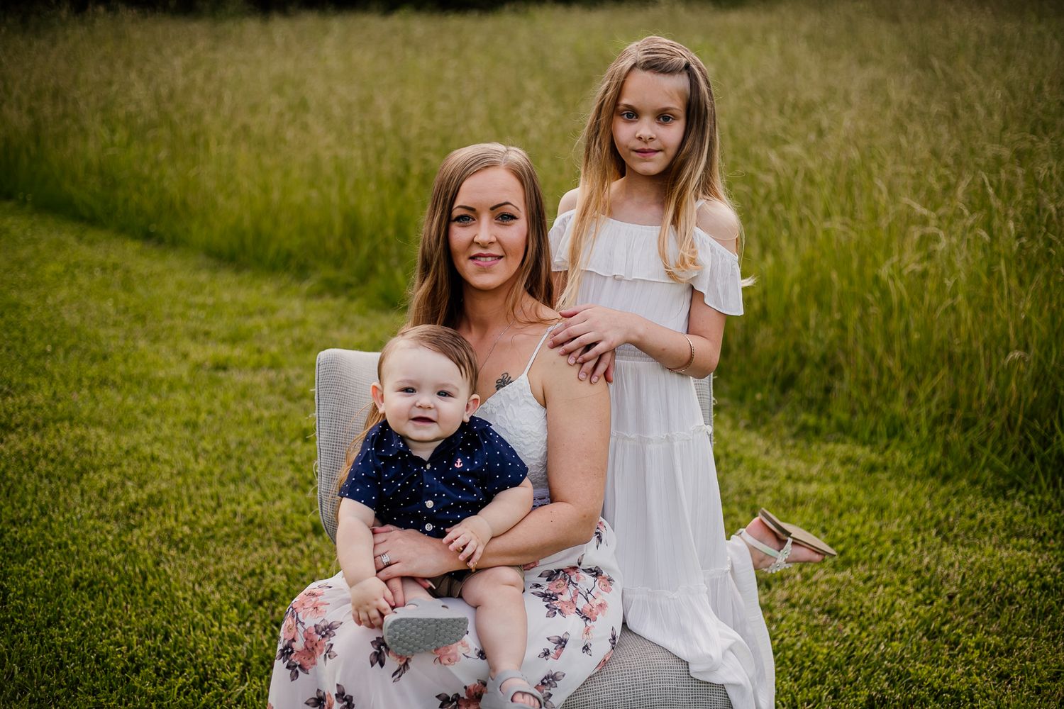 Family portrait session in a golden summer meadow with tall grass.