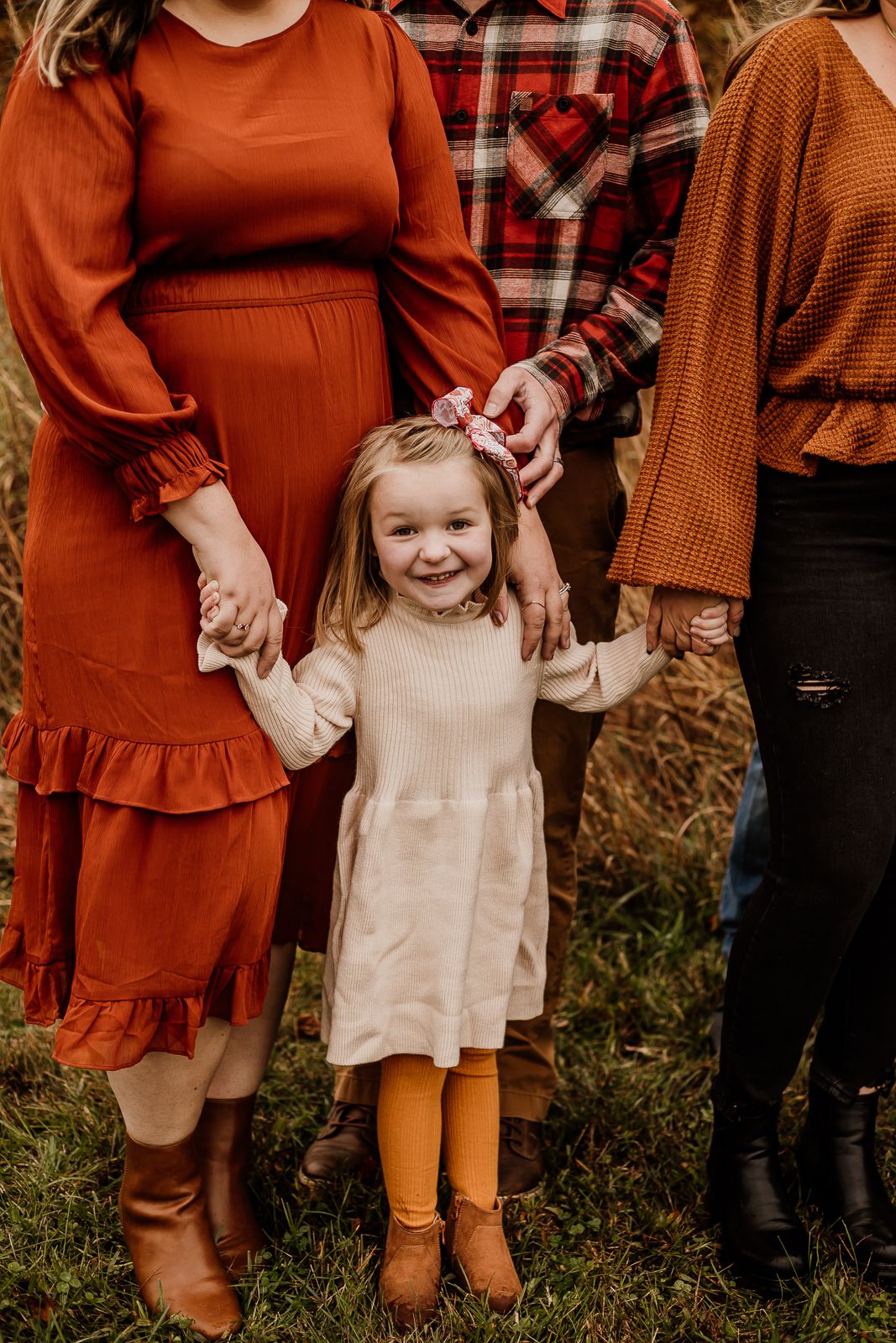 Close-up of family members wearing coordinated autumn colors with rust and brown tones.